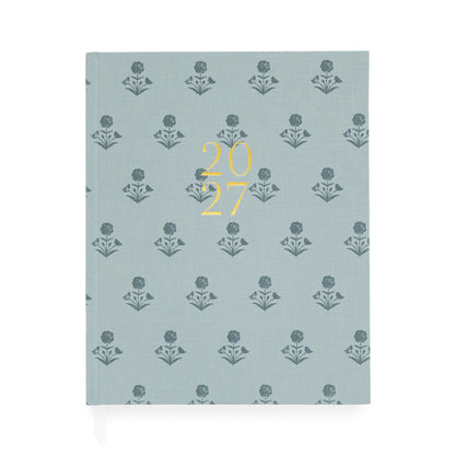 A dusty blue fabric planner with dark blue floral pattern and '2027' stamped on the cover in gold foil with two white ribbon markers
