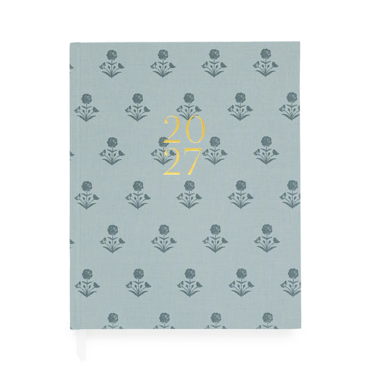 A dusty blue fabric planner with dark blue floral pattern and '2027' stamped on the cover in gold foil with two white ribbon markers