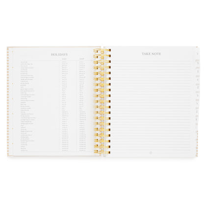 An open spiral-bound planner showing the 'Holidays' and 'Take Note' pages with gold spiral binding