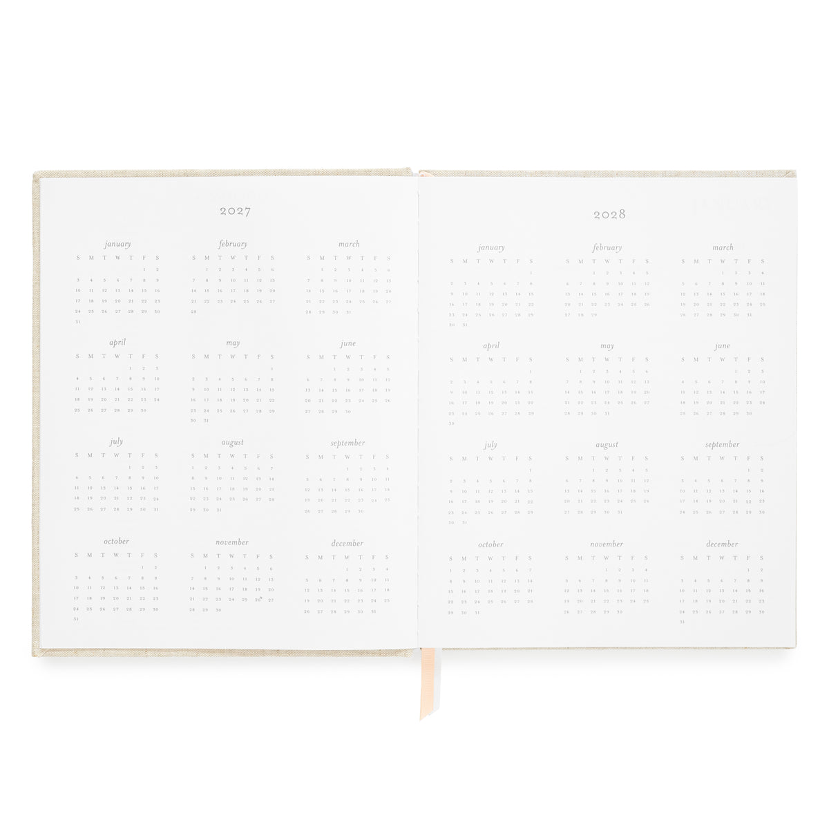 An open planner showing two blank interior spread with 2027 and 2028 calendar grids and a pink and white ribbon marker