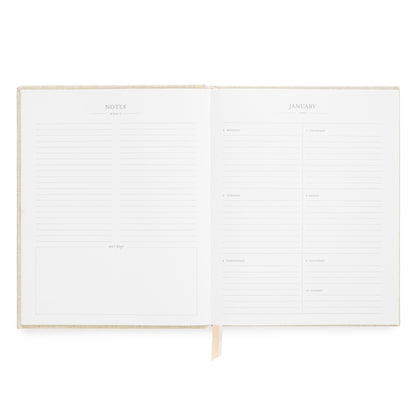 An open planner with lined pages, showing a notes page on the left and a January calendar page on the right