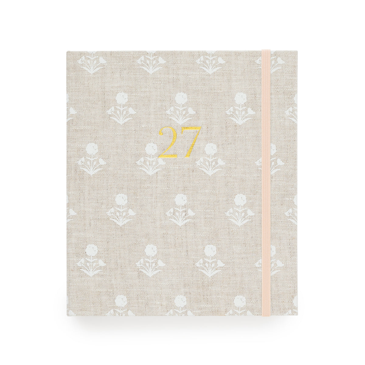 A 2027 fabric planner  with a beige linen cover, featuring a white floral pattern, a gold foil '27' on the front, and a pale pink elastic closure band