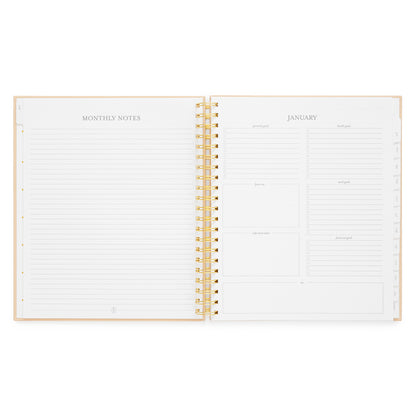 An open spiral-bound planner showing lined monthly note pages on the left and a January goal setting section on the right with 'personal goals,' 'health goals,' 'work goals,' 'financial goals,' and more