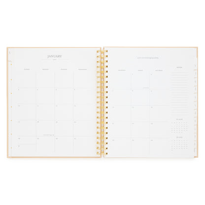 An open spiral-bound planner showing blank January page spread with boxes for the whole month and notes section on the right 