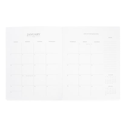 An open white planner or calendar spread showing the January 2027 monthly calendar page with daily boxes, weekly headers, an inspirational quote, and a notes section