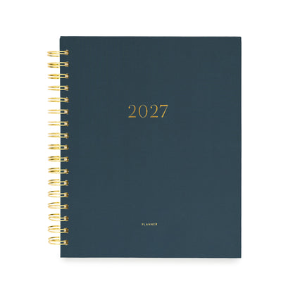 A 2027 spiral-bound planner with a dark navy blue cover and gold foil lettering with '2027' and 'planner' stamped on cover in gold