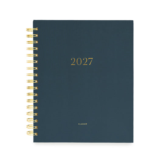 A 2027 spiral-bound planner with a dark navy blue cover and gold foil lettering with '2027' and 'planner' stamped on cover in gold