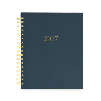 A 2027 spiral-bound planner with a dark navy blue cover and gold foil lettering