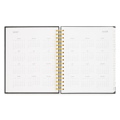 An open spiral-bound planner showing the years 2027 and 2028 with monthly calendar grids on white pages