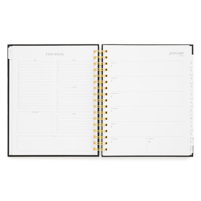 An open weekly planner with white pages, a black cover edge, and gold spiral binding, showing the weekly layout. On the left, planning prompts and on the right weekly layout with spaces for each day of the week