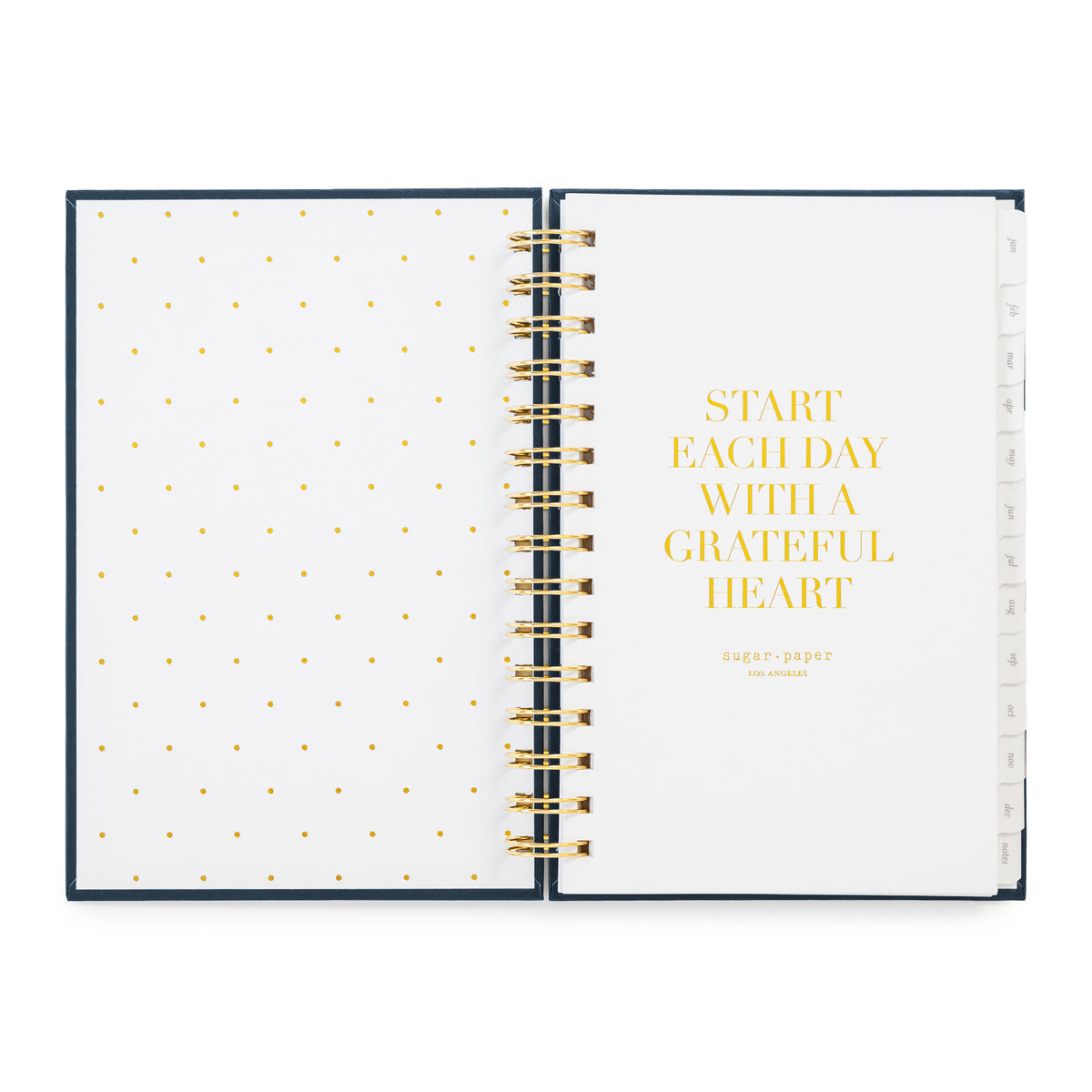 An open spiral-bound planner with white pages, gold polka dots on the left page, and gold text reading 'START EACH DAY WITH A GRATEFUL HEART' on the right page in gold foil