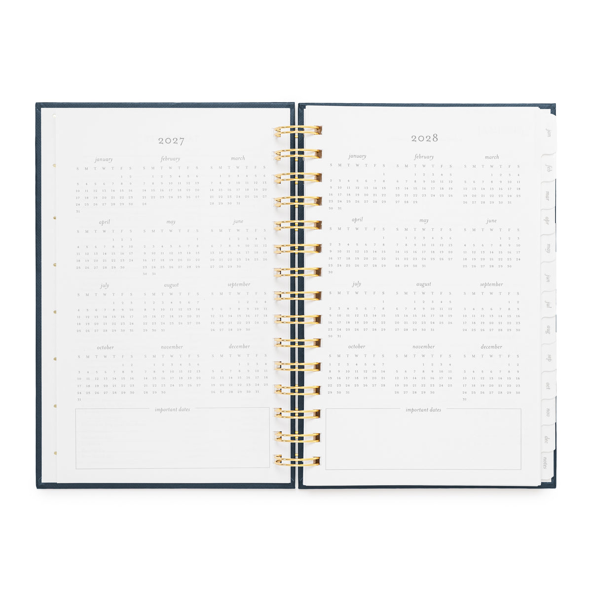 An open spiral-bound planner showing the interior pages for 2027 and 2028 with all dates of the year, with a dark navy cover and gold spiral