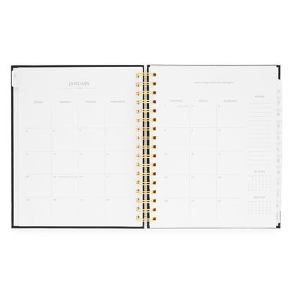 Open spiral planner showing a monthly layout for January 2026 with a gold spiral binding