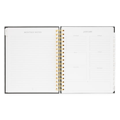 Open spiral planner showing monthly notes page and January 2026 monthly goal prompts