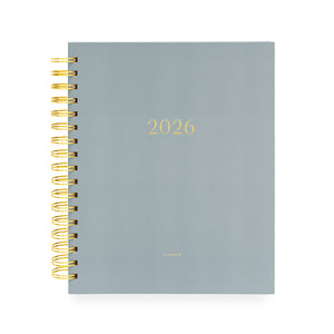 Dusty blue planner with '2026' on cover and a gold spiral binding