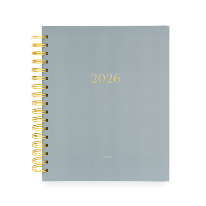 Dusty blue planner with '2026' on cover and a gold spiral binding