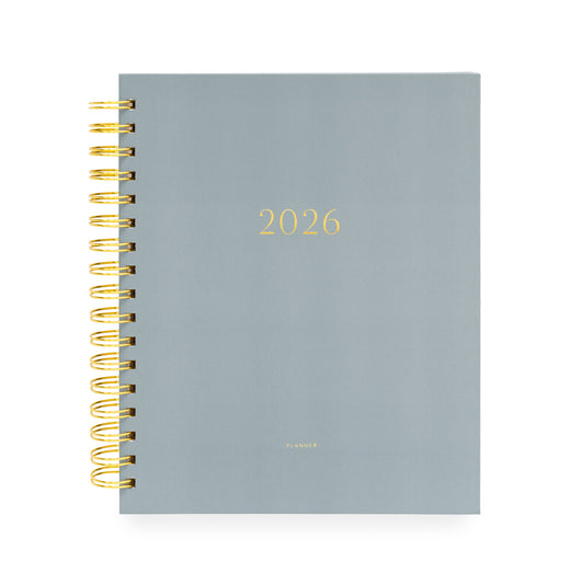 Dusty blue planner with '2026' on cover and a gold spiral binding