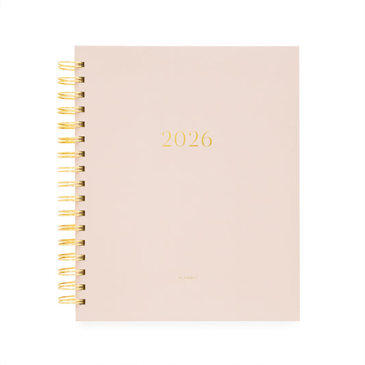 Blush pink planner with '2026' printed on it, featuring a gold spiral binding.