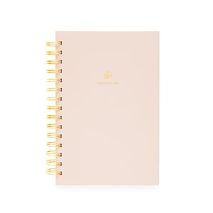 Blush pink planner with gold spiral binding with twenty-six on the cover and a god flower