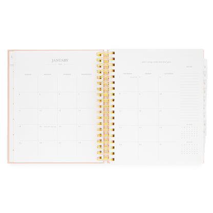 Open spiral planner showing january monthly calendar with a gold spiral binding