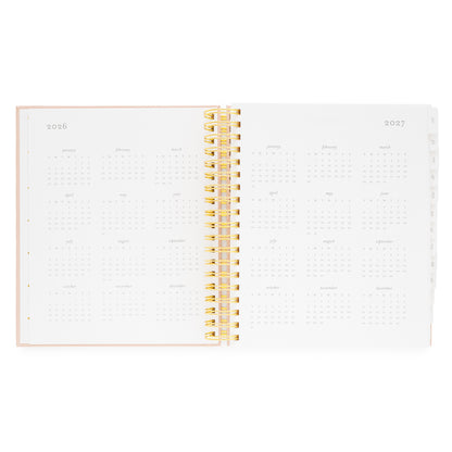Open spiral planner with gold spiral binding and 2026 + 2027 months