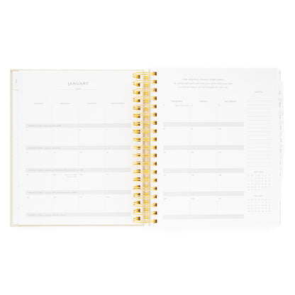 Open daily spiral planner showing January monthly layout with gold spiral binding with weekly goals and monthly project focus