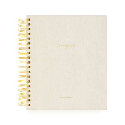 Beige planner with gold spiral binding and 'Twenty Six and Daily Planner' in gold foil