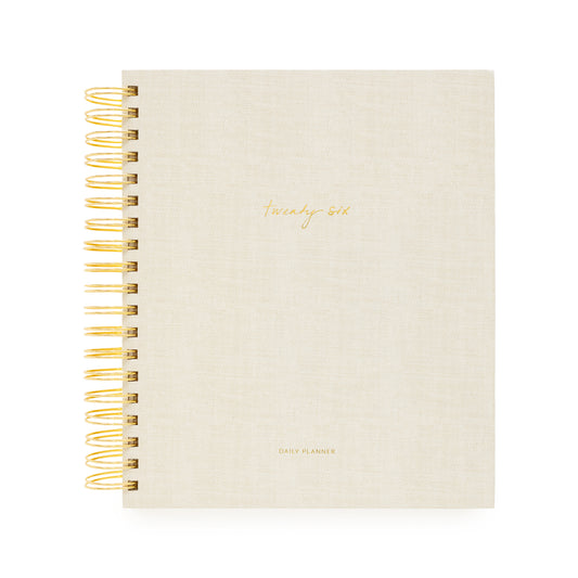 Beige planner with gold spiral binding and 'Twenty Six and Daily Planner' in gold foil