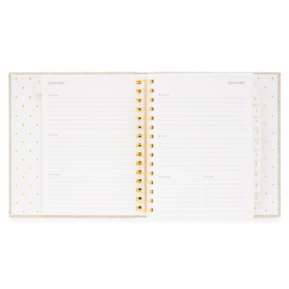 An open concealed agenda with gold spiral with weekly planning pages
