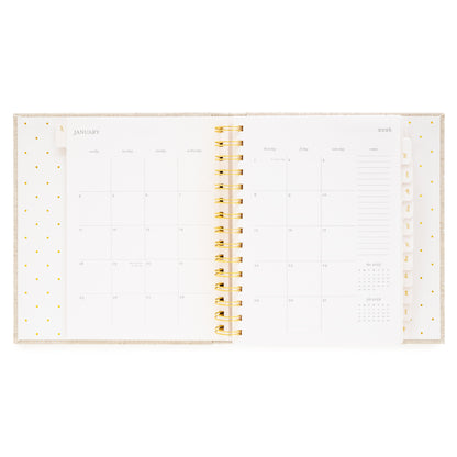 Open concealed agenda with gold spiral and monthly grid layout for January 2026