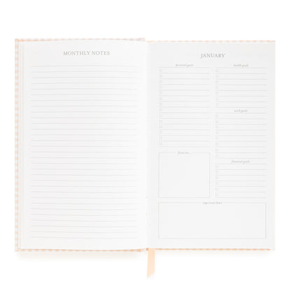 Open small bound agenda with monthly notes section and goal prompts for January