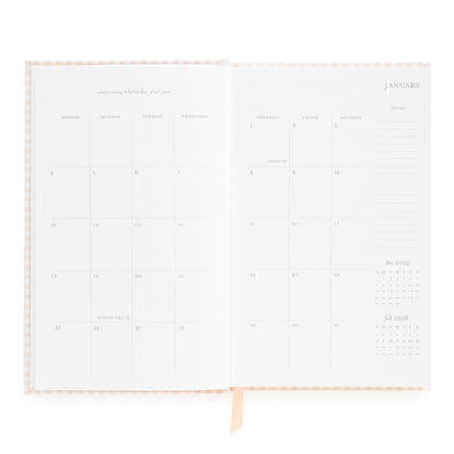 Open small bound agenda with january monthly grid with inspirational quote and space for notes on the side