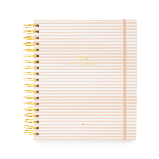 Daily planner with pink and white stripes and a pink elastic with a gold coil spiral binding. Cover is stamped in gold foil with 'daily planner' and '2027'