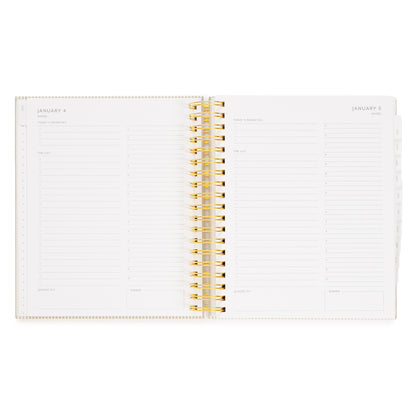 An open spiral-bound planner with gold wire binding to weekly and daily layouts of january days