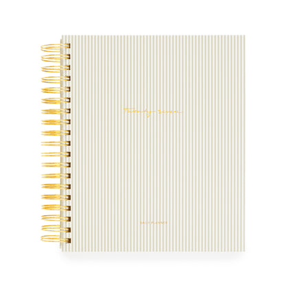 A beige and white stripe spiral bound planner with a gold coil and 'twenty-seven' and 'daily planner' stamped in gold foil on the cover
