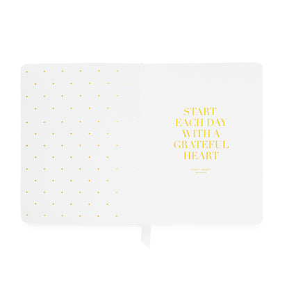 An open planner with 'start each day with a grateful heart' in gold foil with gold foil dot pattern on the left side
