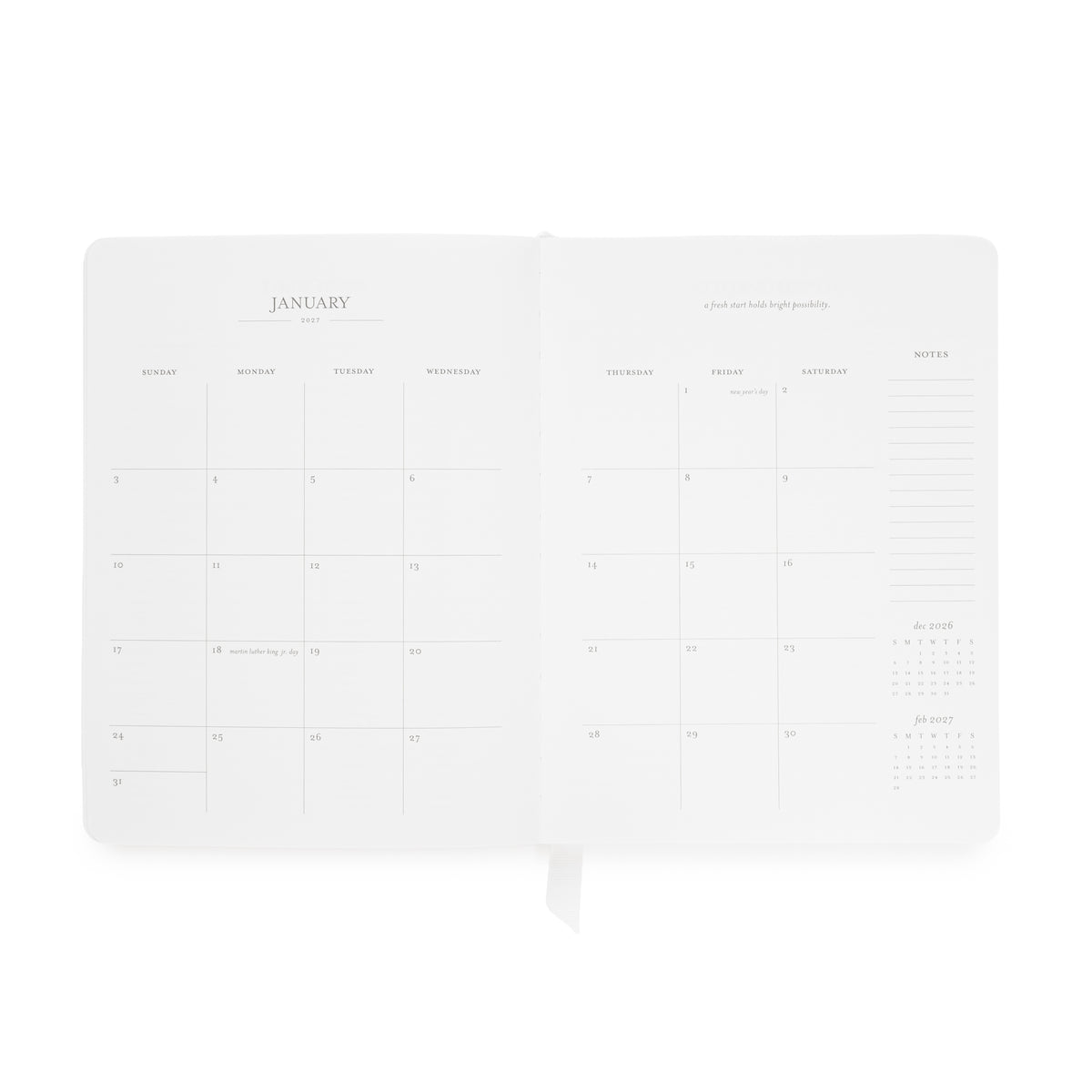 An open white planner showing the January page spread with minimalist columns for daily planning, a notes section on the right side, and a quote at the top