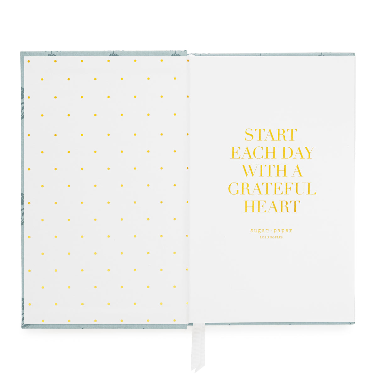 An open planner on a white background, showing a white left page with small gold foil polka dots and a white right page with the gold text 'START EACH DAY WITH A GRATEFUL HEART' and the brand name 'sugar_paper' below.