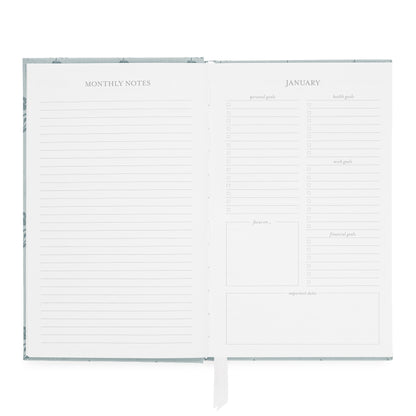 An open monthly agenda with lined 'MONTHLY NOTES' pages and a January overview of 'personal goals,' 'health goals,' 'work goals,' 'financial goals,' 'focus on,' and 'important docs'