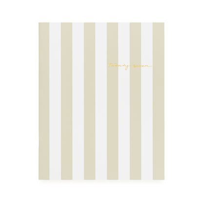 A flat monthly planner with a beige and white stripe pattern with '2027' stamped on cover in gold foil
