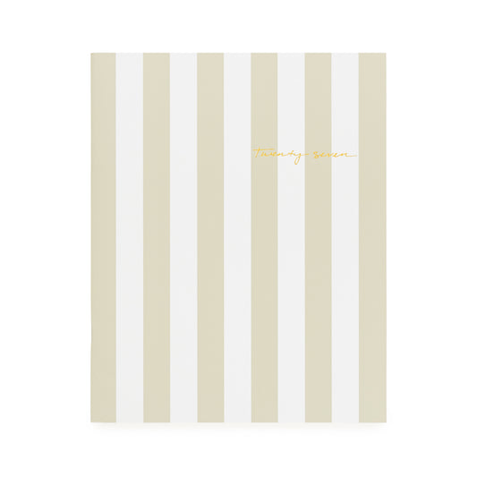 A flat monthly planner with a beige and white stripe pattern with '2027' stamped on cover in gold foil
