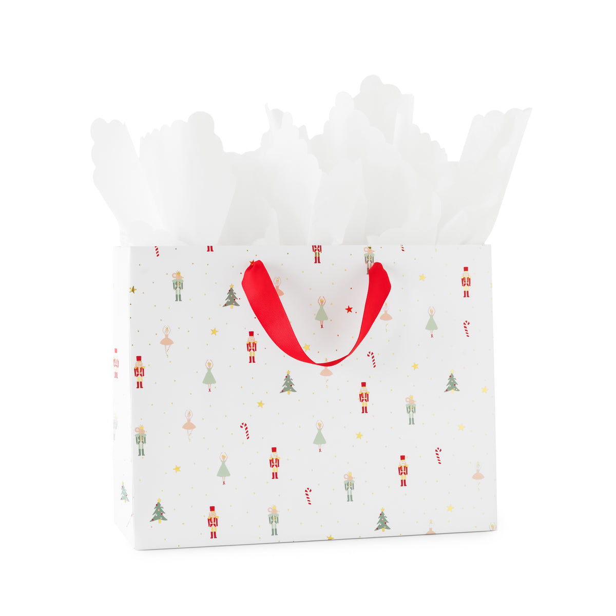 A white gift bag with a festive Christmas pattern of nutcrackers, soldiers, trees, and candy canes, featuring red ribbon handles and white tissue paper