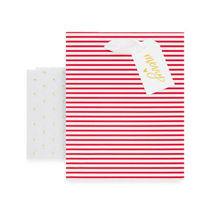Red and white striped gift bag with a white gift tag with 'merry' and a heart printed in gold foil with gold dot tissue paper