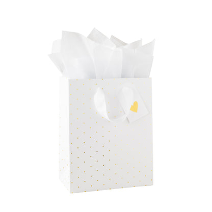 White gift bag with gold polka dots, white tissue paper, and a gold heart tag