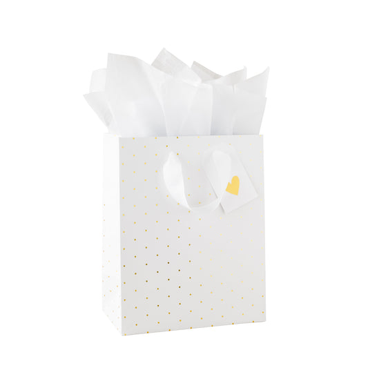 White gift bag with gold polka dots, white tissue paper, and a gold heart tag