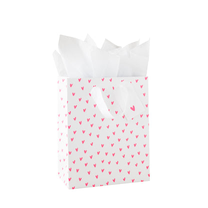 White gift bag with neon pink heart pattern, white tissue paper and a white gift tag with a neon heart pattern