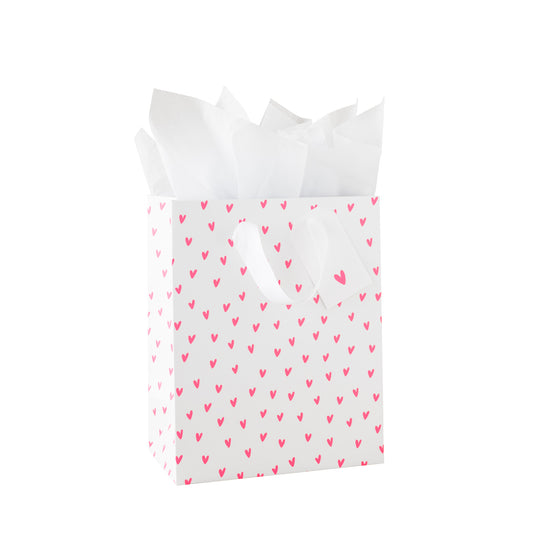 White gift bag with neon pink heart pattern, white tissue paper and a white gift tag with a neon heart pattern