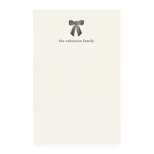 Note pad with a black bow design and 'the robinson family' text on cream paper