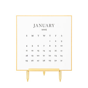 White calendar card with black letterpress ink for January 2026 on a brass stand