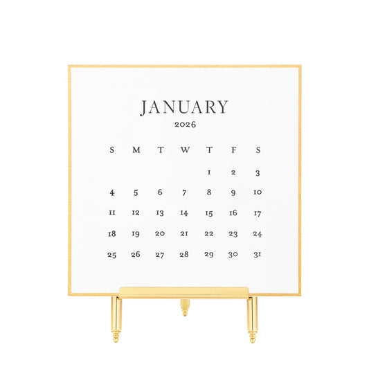 White calendar card with black letterpress ink for January 2026 on a brass stand